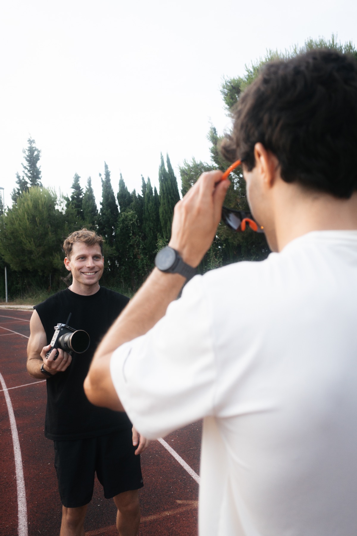 Un miembro del equipo sostiene una cámara y conversa con otra persona en una pista de atletismo