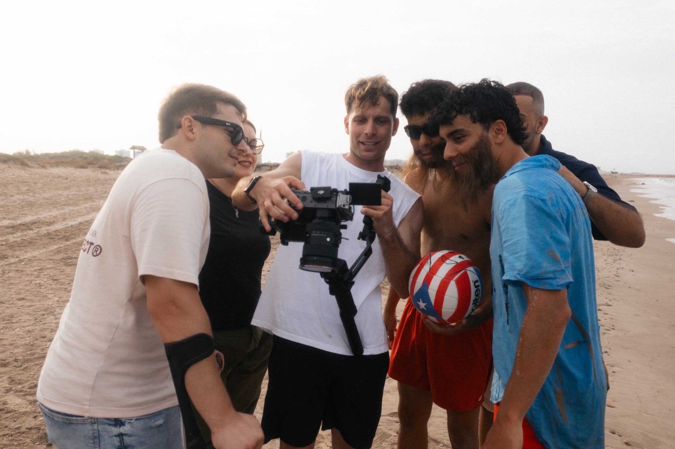 El equipo y Los Sepuls revisan juntos una toma en la pantalla de la cámara, en la playa